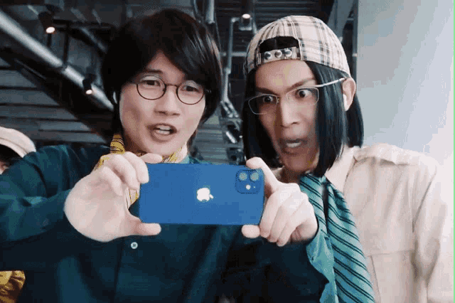 two men are taking a picture of themselves with a blue iphone