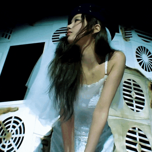 a woman in a white dress is standing in front of a wall with black and white stripes