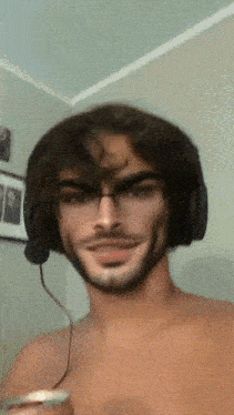 a man without a shirt is wearing headphones and holding a can