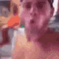 a man without a shirt is taking a selfie with a blurry background .