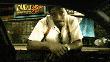 a man in a car with a budweiser sign in the background