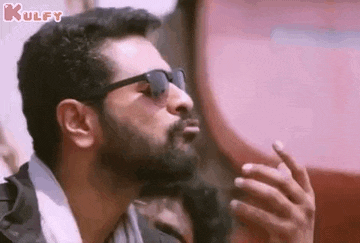 a man wearing sunglasses is blowing a kiss .