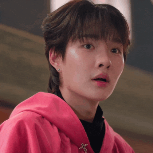 a close up of a person 's face with a pink jacket on