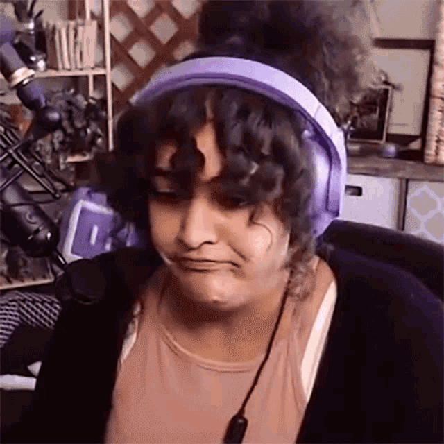 a woman wearing purple headphones is sitting in front of a microphone .