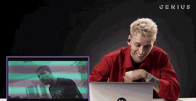 a man sitting in front of a laptop with genius written on the bottom