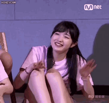 a girl is sitting on the floor with her legs crossed and laughing .