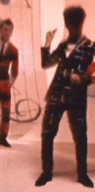 a man in a suit is dancing in a room with other people