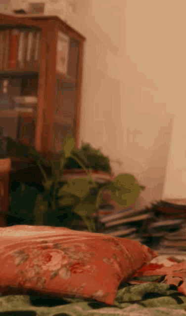 a floral pillow is laying on a bed in front of a bookshelf