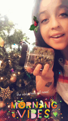 a girl is holding a jar of marijuana in front of a christmas tree with morning vibes written on the bottom