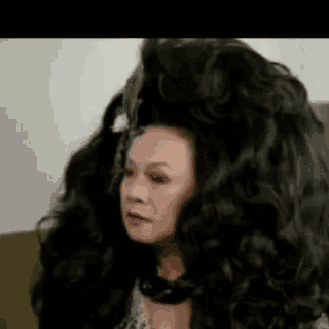 a woman with very long hair is wearing a wig and making a funny face .