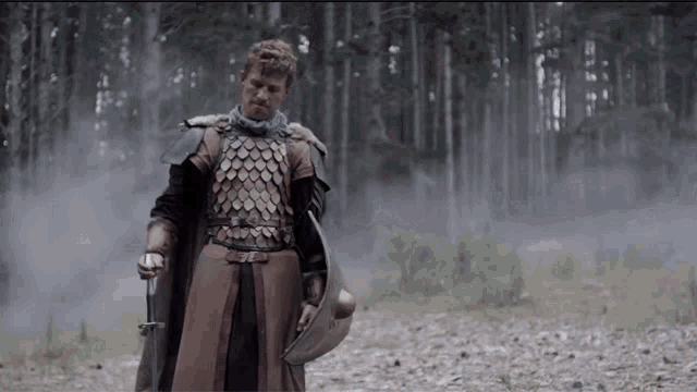 a man in armor holding a sword and a helmet