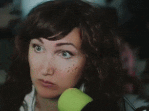 a woman with a surprised look on her face is holding an apple in her hands .