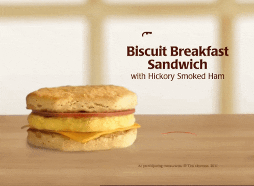 a biscuit breakfast sandwich with hickory smoked ham on a wooden table