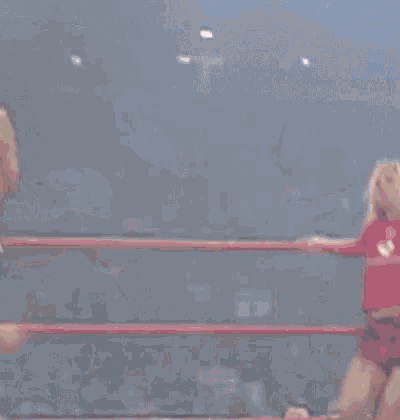 two women are wrestling in a ring and one of them is getting kicked in the face .