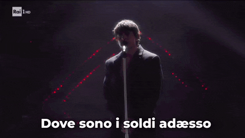 a man singing into a microphone with the words dove sono i soldi adesso written below him