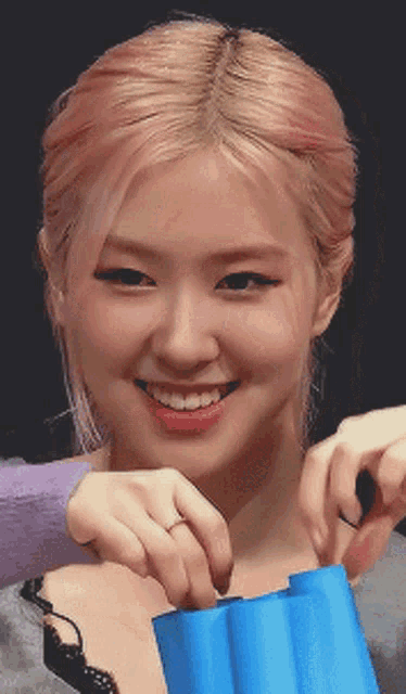 a woman with pink hair is smiling while holding a blue bag