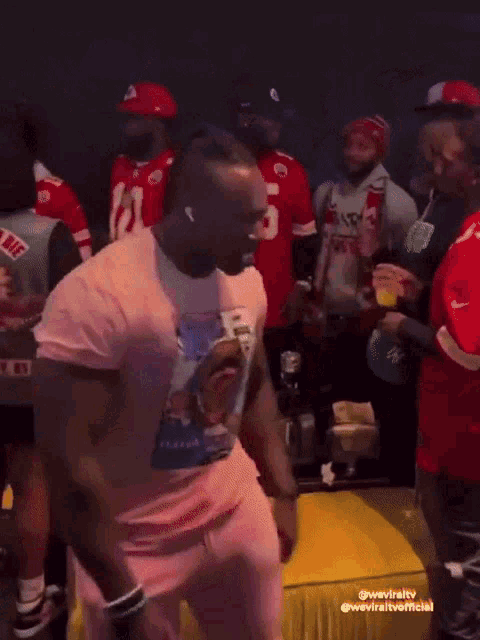 a man in a pink shirt dancing in a crowd
