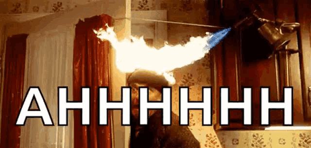 a person is holding a lighter with flames coming out of it and the word ahhhh is above them .