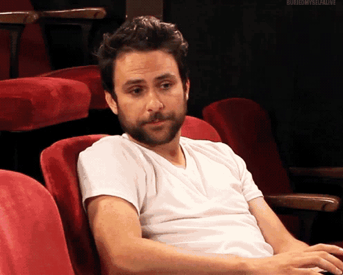 a man with a beard is sitting in a red chair with a white shirt on