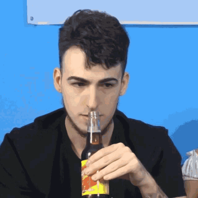 a man drinking from a bottle with a yellow label that says ' strawberry ' on it