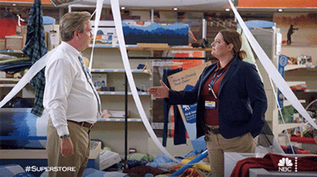 a man and a woman are standing in a store talking to each other