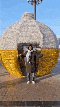 a person standing in front of a giant christmas ornament