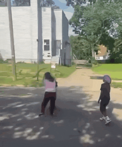 a boy and a girl are walking down a dirt road in front of a white house