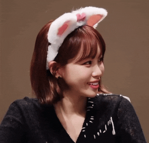 a woman wearing a cat ear headband smiles for the camera