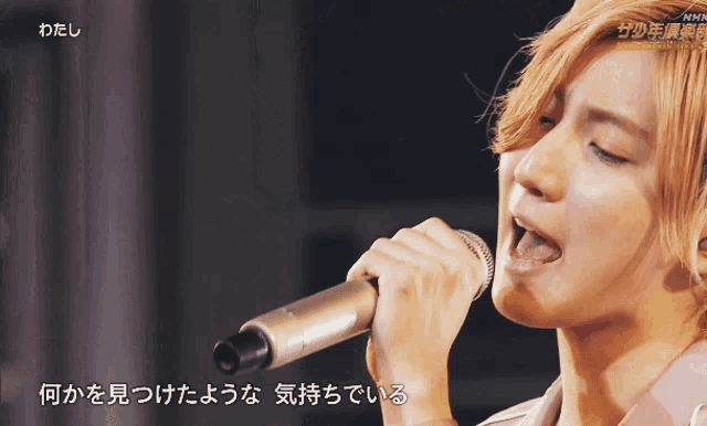 a close up of a person singing into a microphone with nhn written in the corner