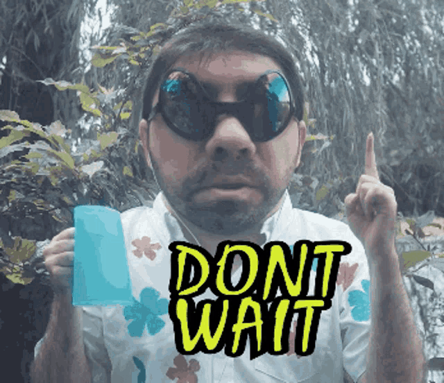 a man wearing sunglasses and a shirt that says dont wait holds up his finger