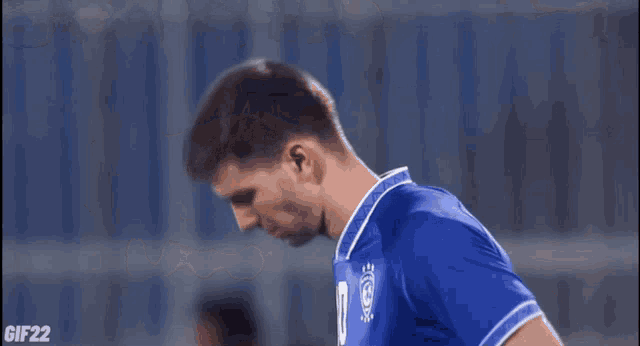 a soccer player in a blue jersey is bending over and looking down .