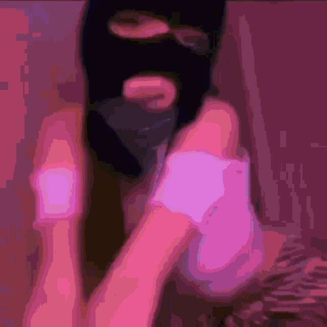 a woman wearing a ski mask and a pink shirt is sitting on a pink couch .