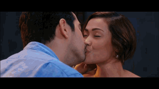 a man and a woman are kissing in a dark room