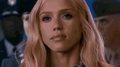 a close up of a woman 's face with a police officer behind her .
