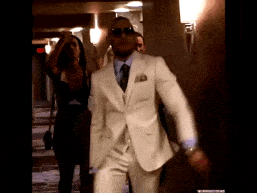 a man in a white suit and sunglasses is dancing