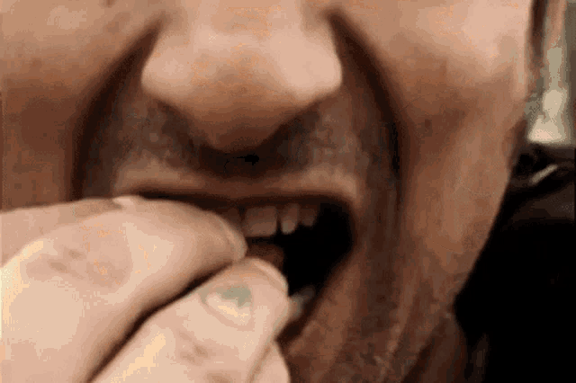 a close up of a man 's mouth with a tattoo on his thumb .