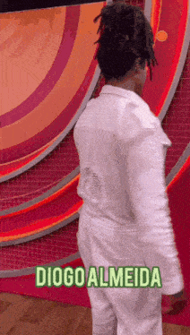 a man with dreadlocks is wearing a white shirt and white pants and the name diogo almeida is on the bottom right