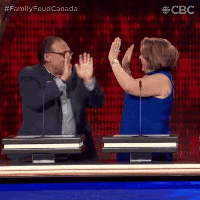 a man and a woman are giving each other a high five during a game show .