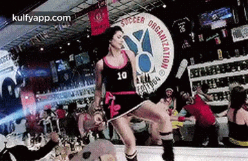 a woman is dancing on a stage in front of a crowd in a bar .
