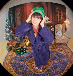 a person wearing a purple robe and a green hat is standing on a rug in front of a christmas tree