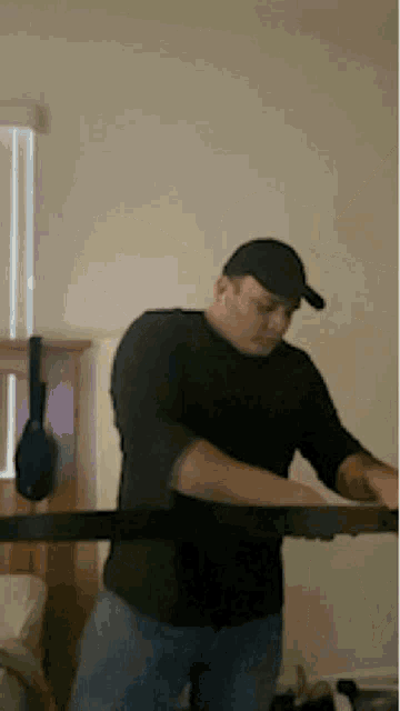 a man wearing a black shirt and a hat is standing in a room