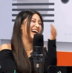 a woman is laughing in front of a microphone