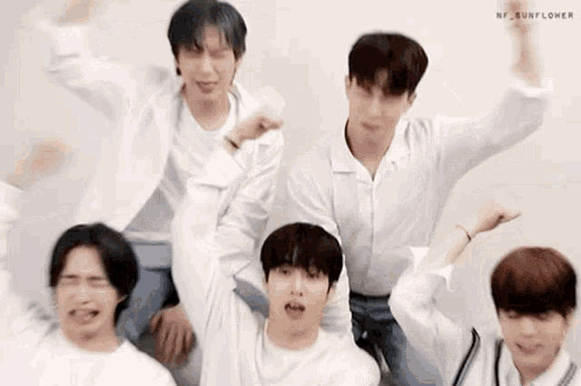 a group of young men are posing for a picture together while sitting on the floor .