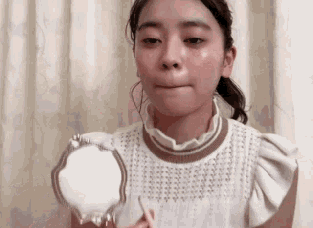 a young woman is looking at her face in a mirror .