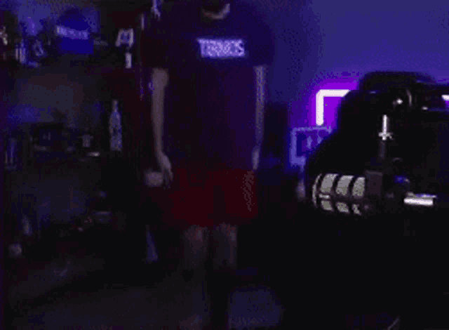 a man wearing a t-shirt that says terroos is standing in a dark room .