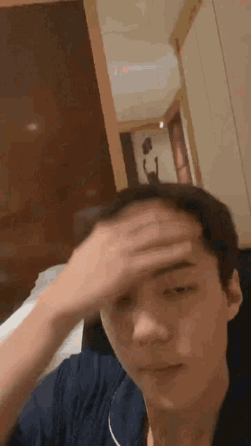 a man in a blue shirt is holding his head