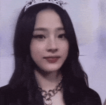 a close up of a woman wearing a tiara and a chain necklace .