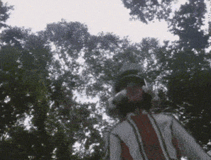 a person wearing a helmet and headphones is standing in front of trees .