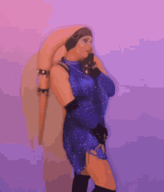 a woman in a blue dress and black gloves is standing in front of a purple background .