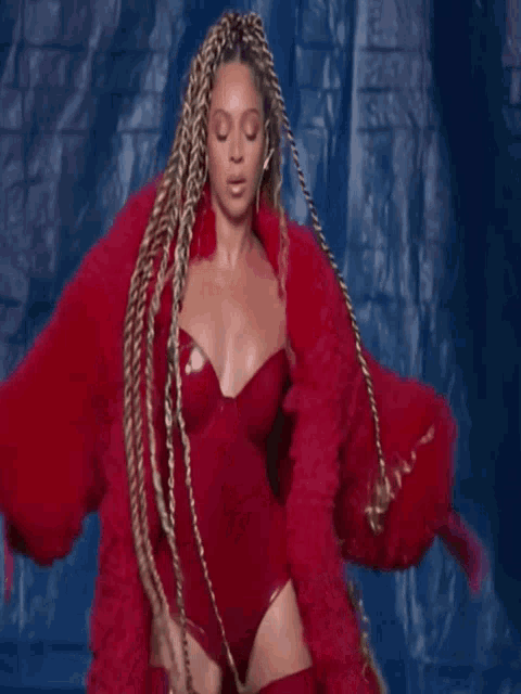 a woman with braids is wearing a red bodysuit and a red fur coat
